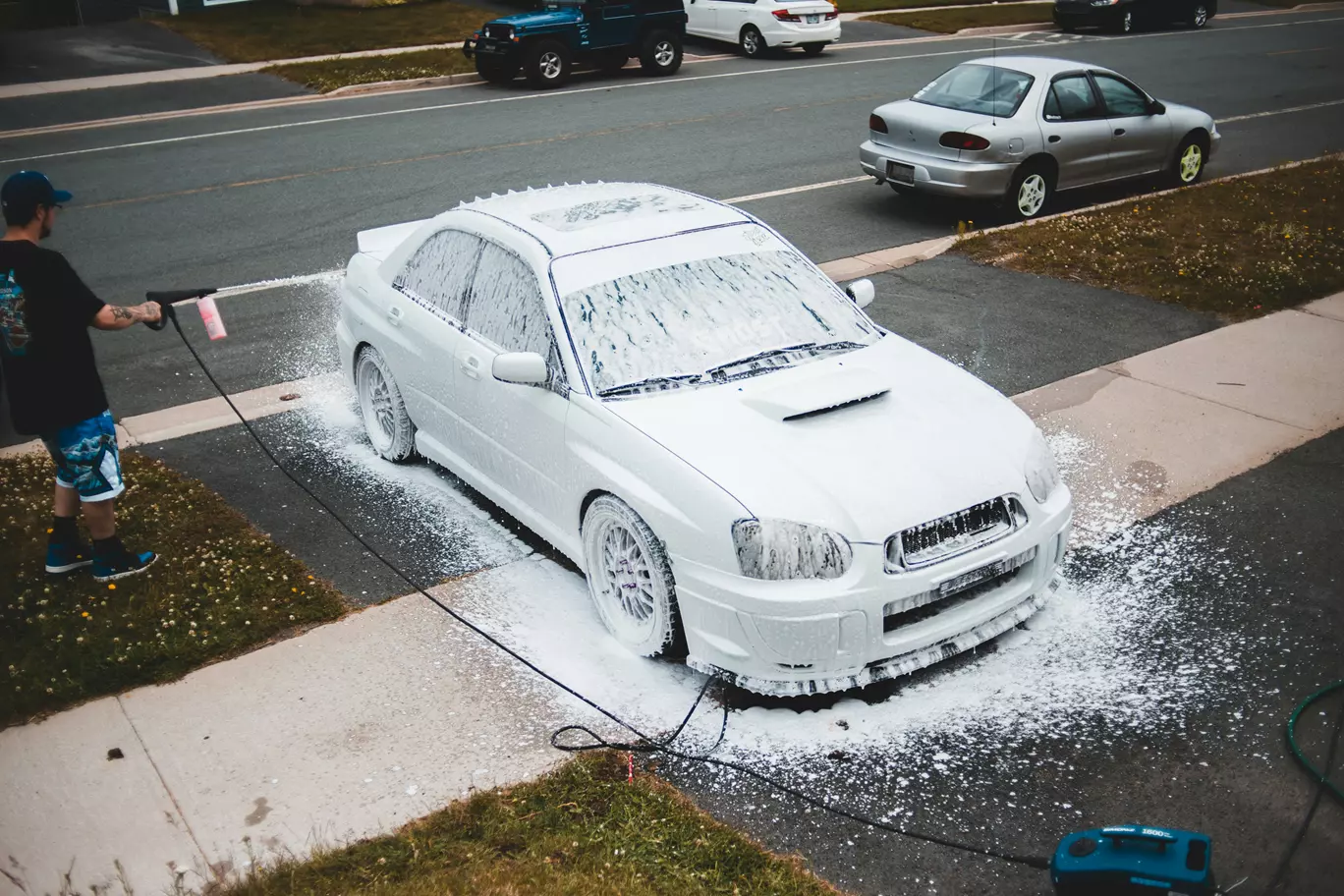 Sedan parked curbside on a quiet street with overcast sky
